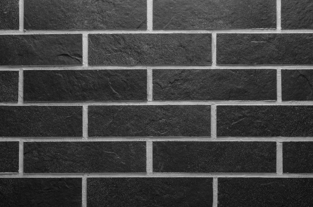 Anthracite-black brick masonry BR09 Volcanic Anthracite with light joints and a grainy stone surface