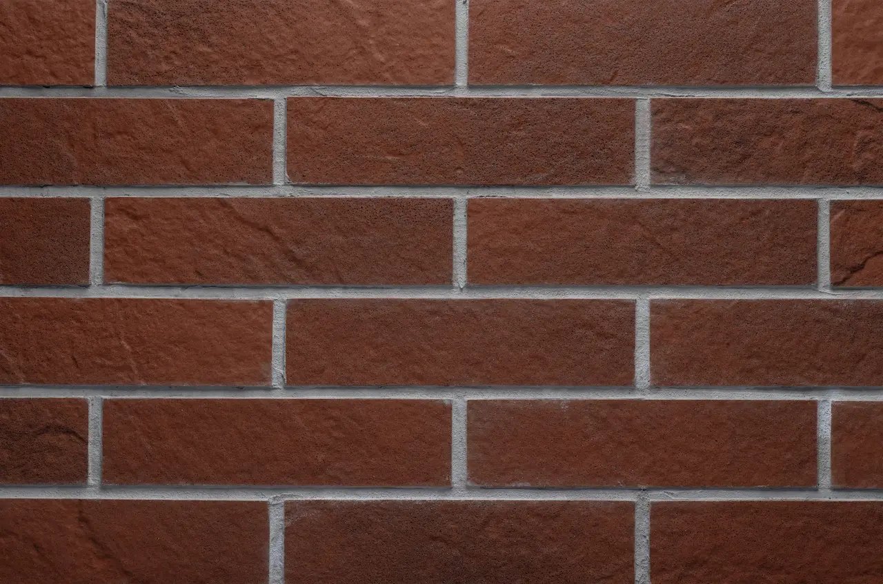 Terracotta brick masonry BR10 Loft Red Clay with light-gray joints and a textured stone surface