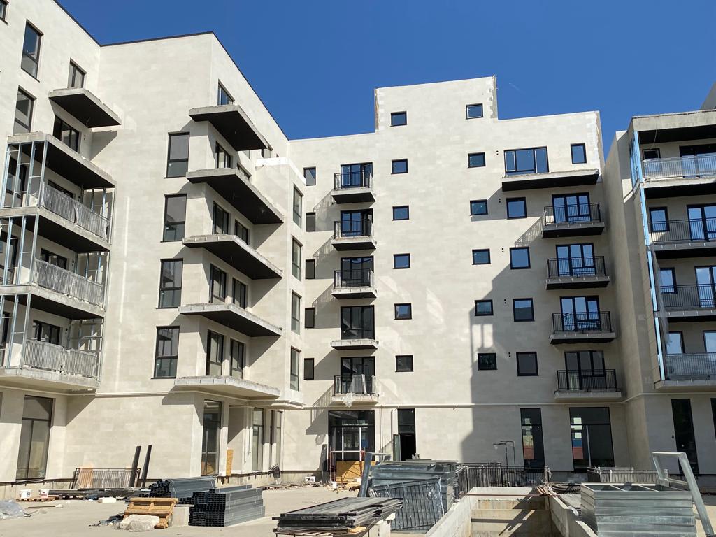 Contemporary blocks with balconies in beige flexible stone, scaffolding on the left facade