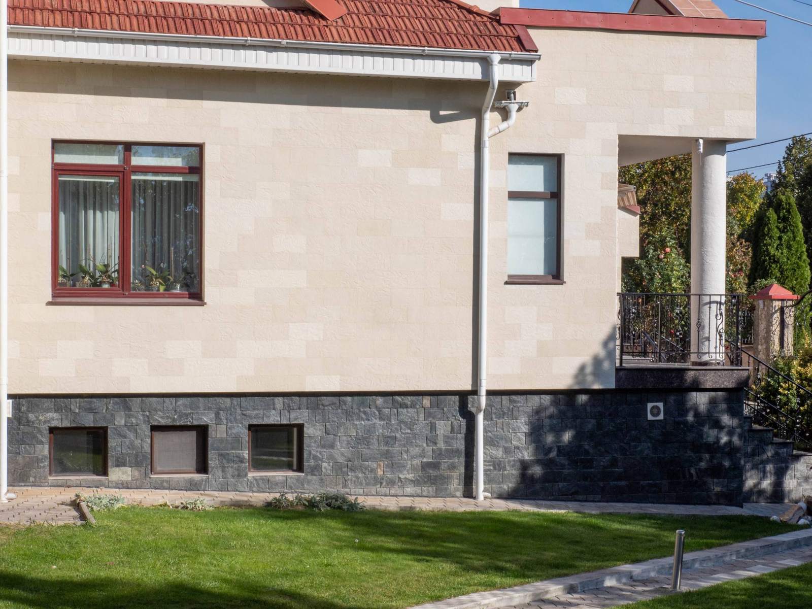 Side facade with windows, a balcony with wrought-iron railing and beige flexible stone