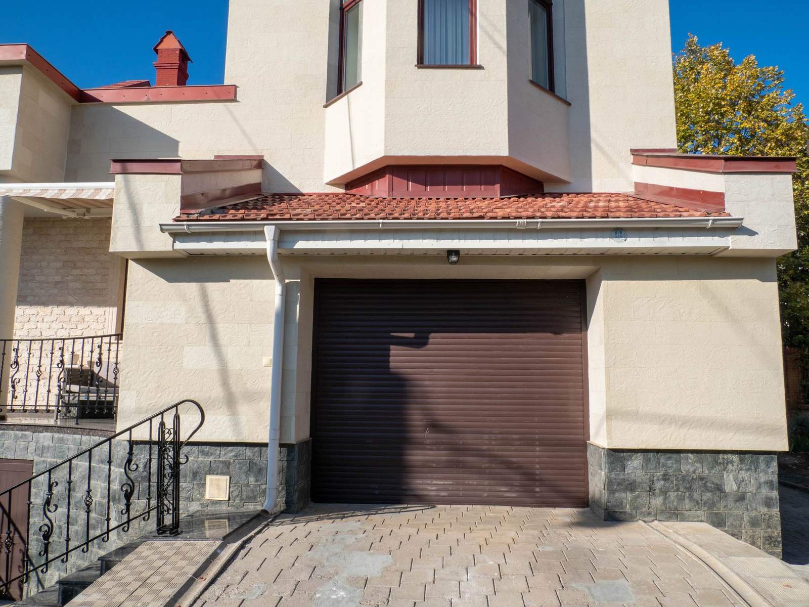 Brown garage door under a gable, Tender Rock flexible stone facade and paved driveway