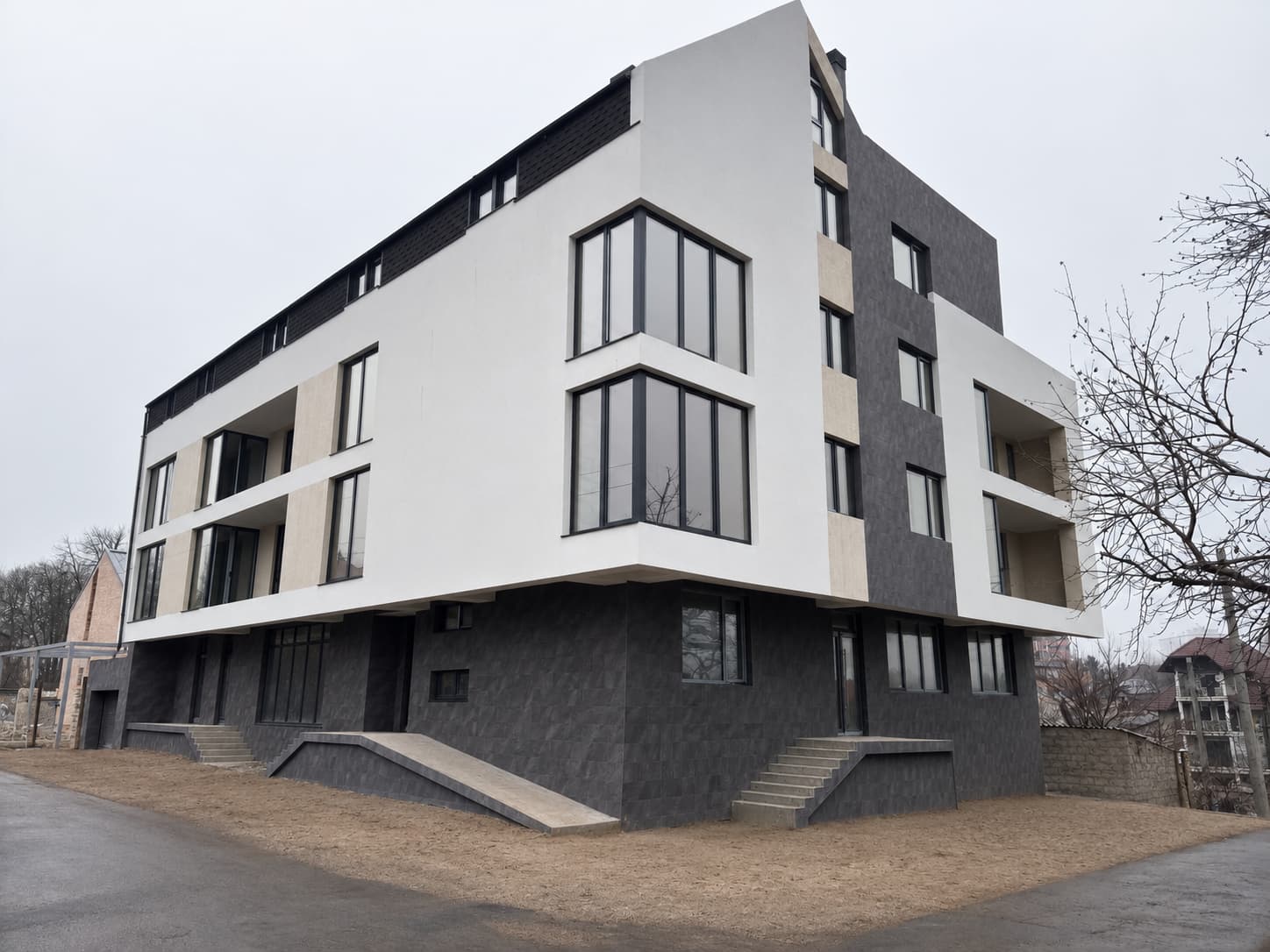 The whole building from the corner: Royal Granite ground floor, white upper floors, dark-clad rear wing