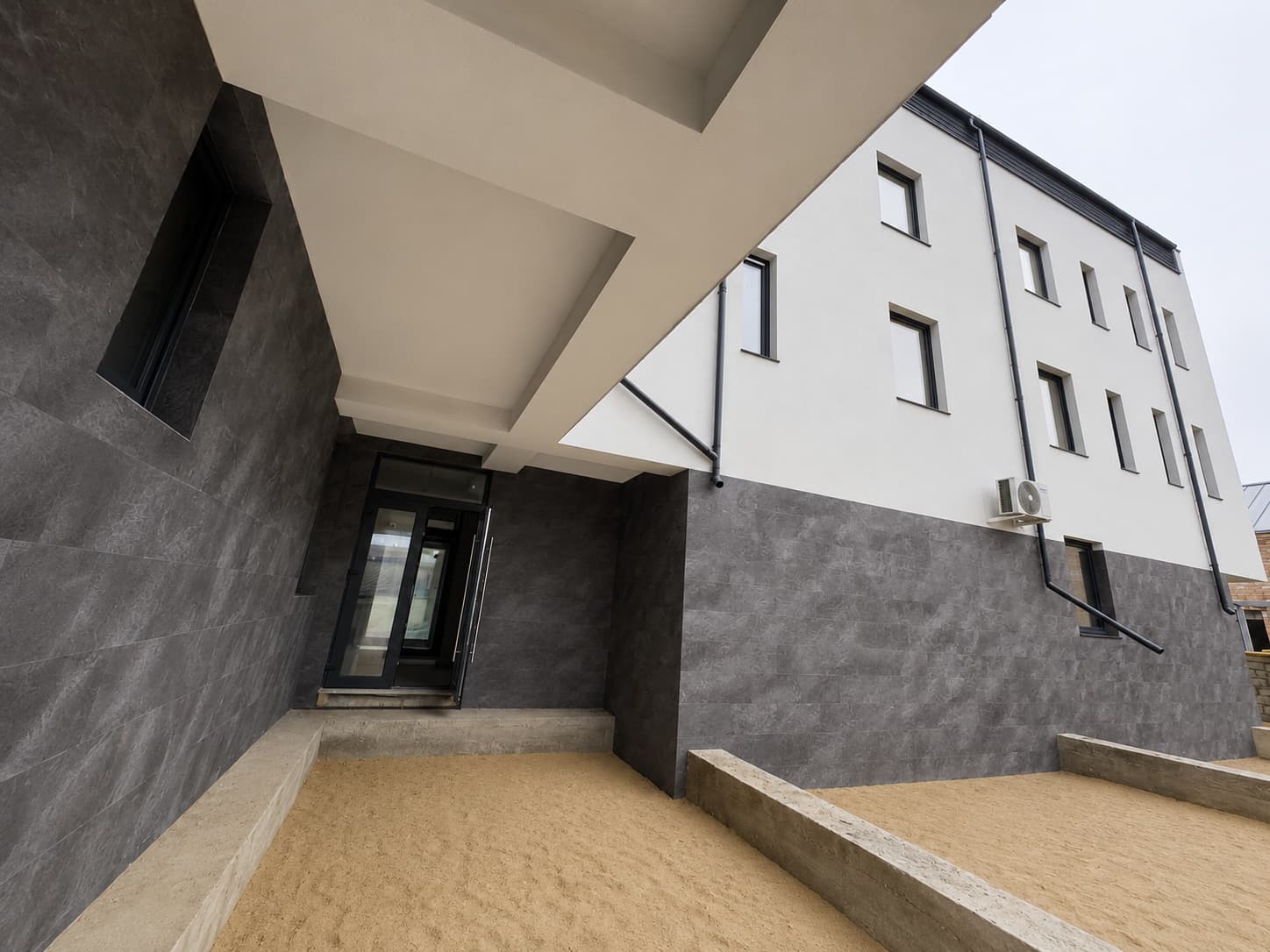 Secondary entrance under the overhang, Royal Granite walls and concrete steps