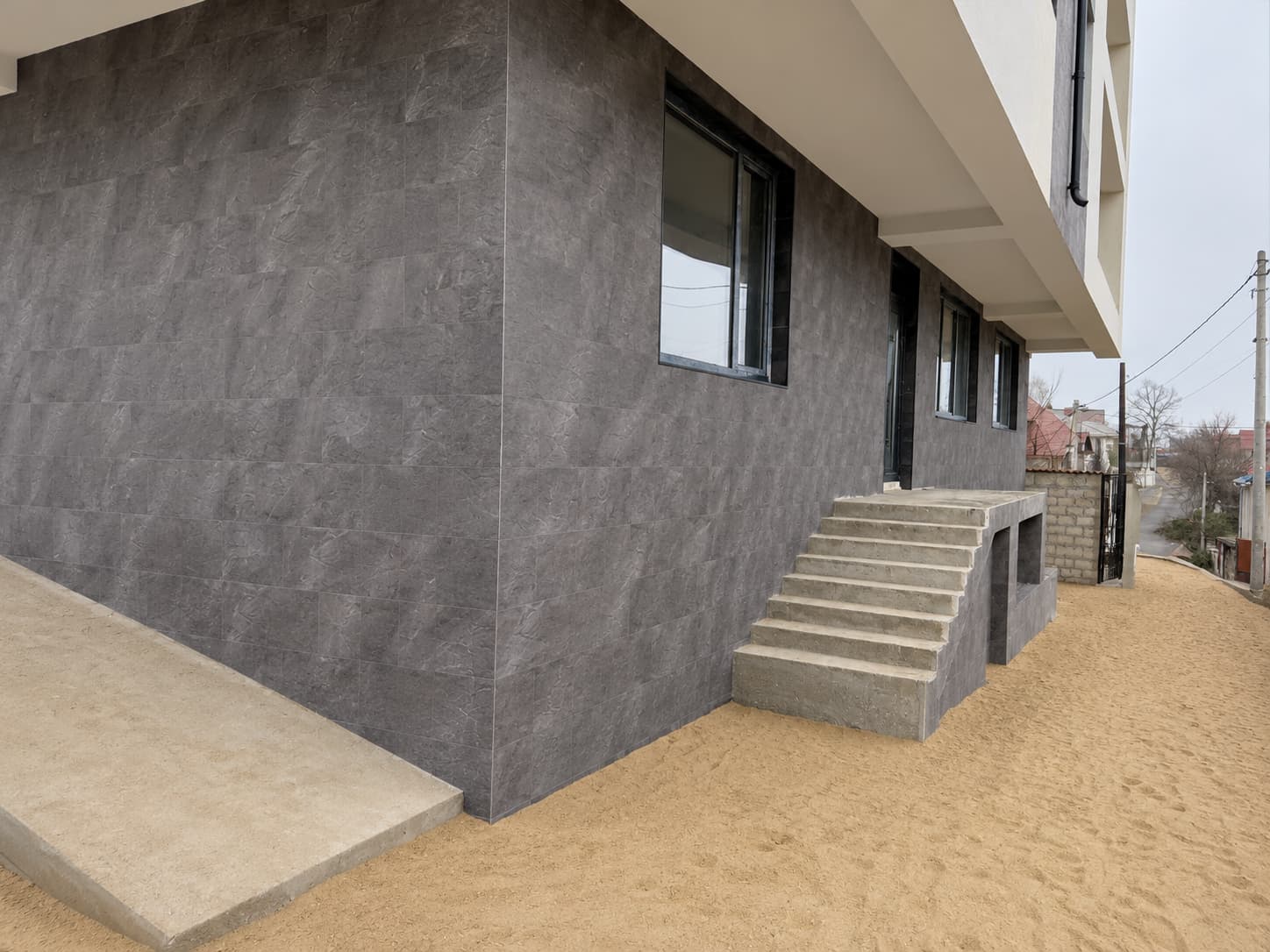 Ground-floor corner clad in Royal Granite, concrete ramp and steps to the entrance