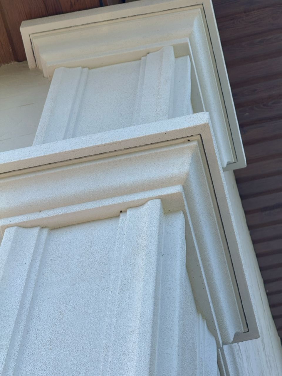White pilaster capital above the light flexible stone wall
