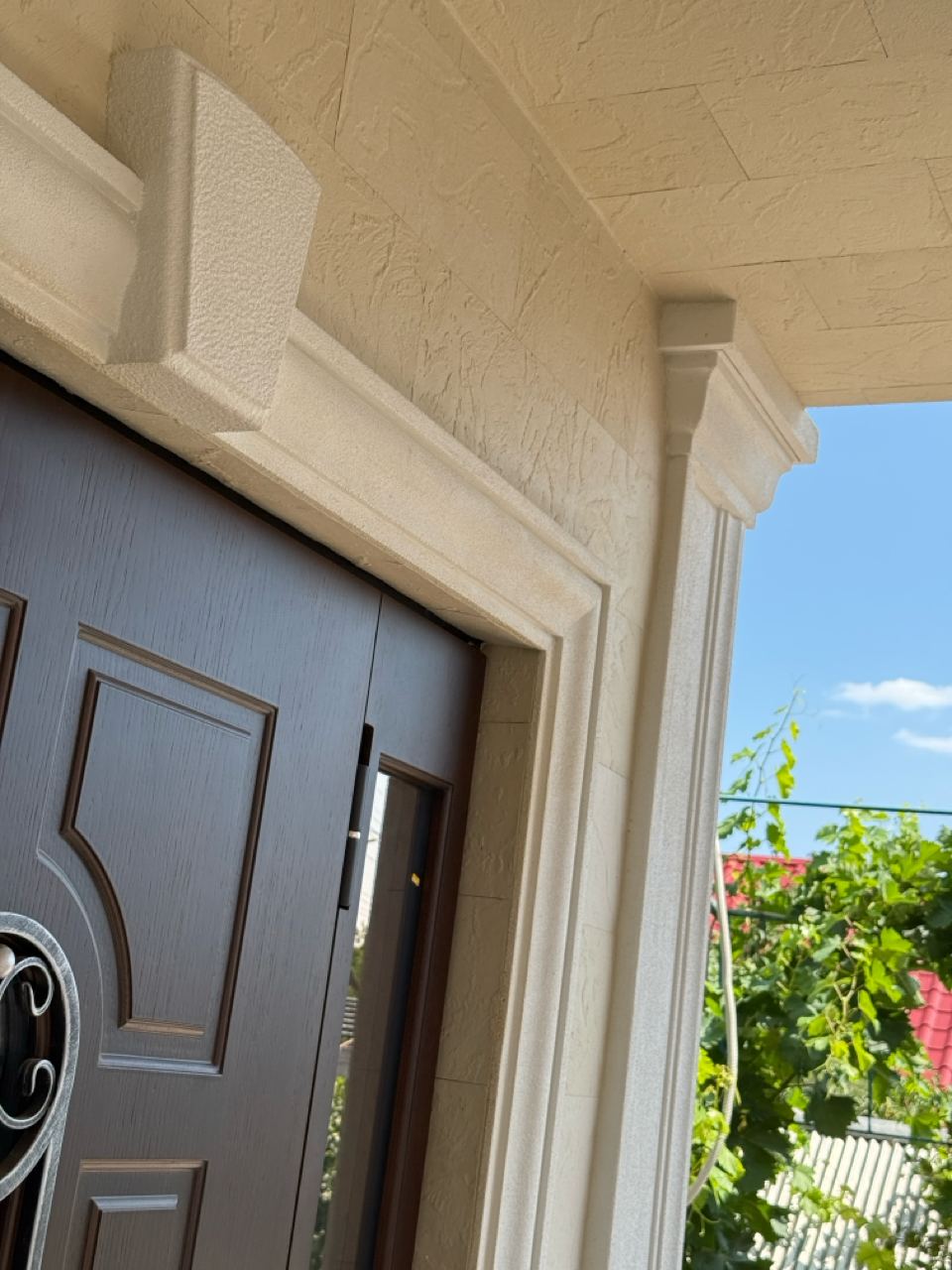 Entrance door between white pilasters with light flexible stone above