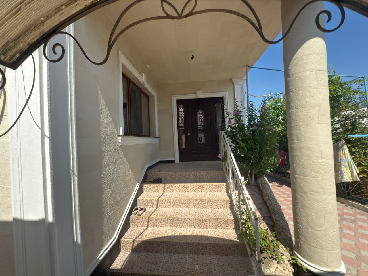 Entrance with steps, wrought-iron canopy and a round column clad in flexible stone