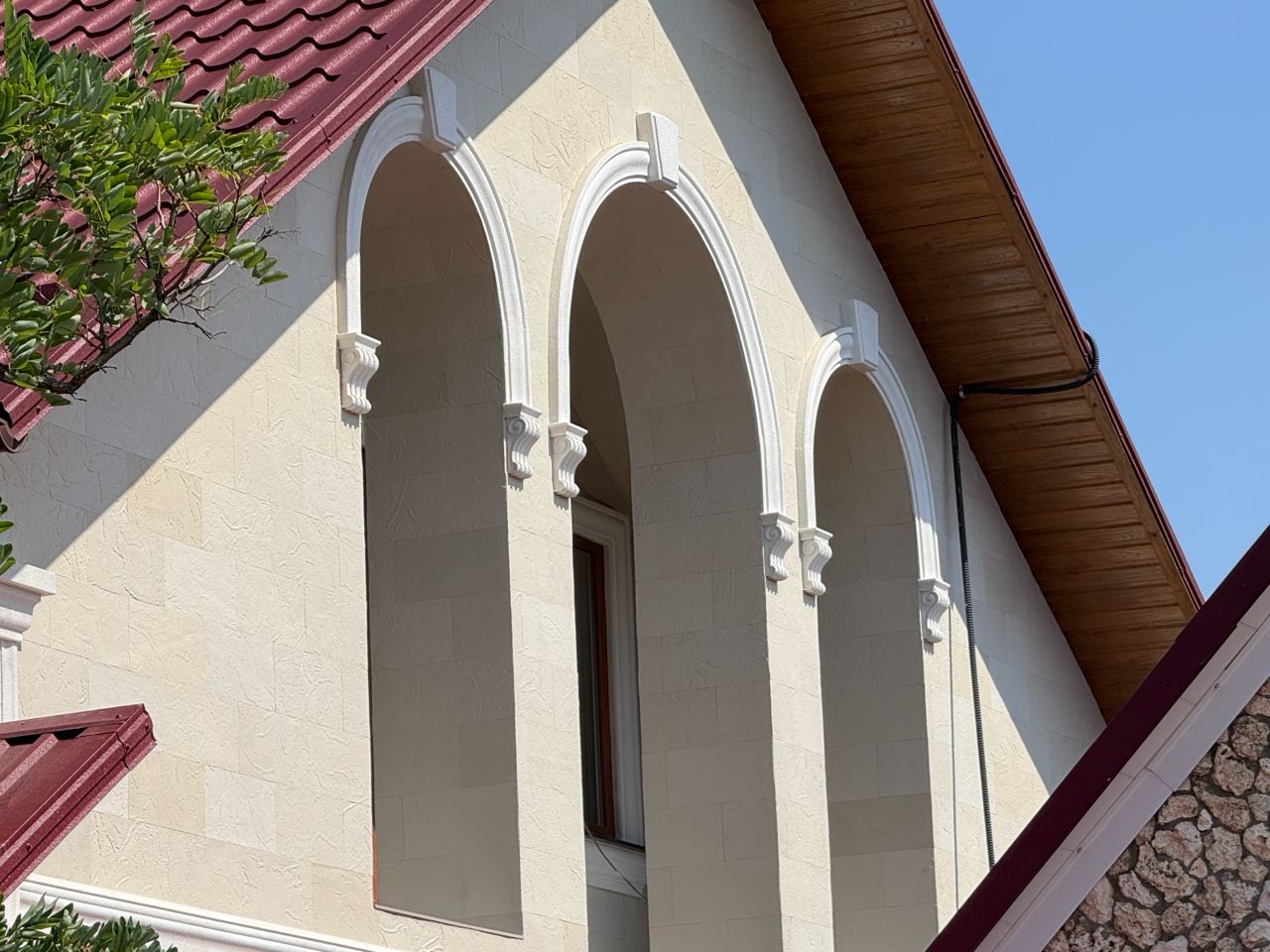 Window arch clad in flexible stone, keystone and white consoles