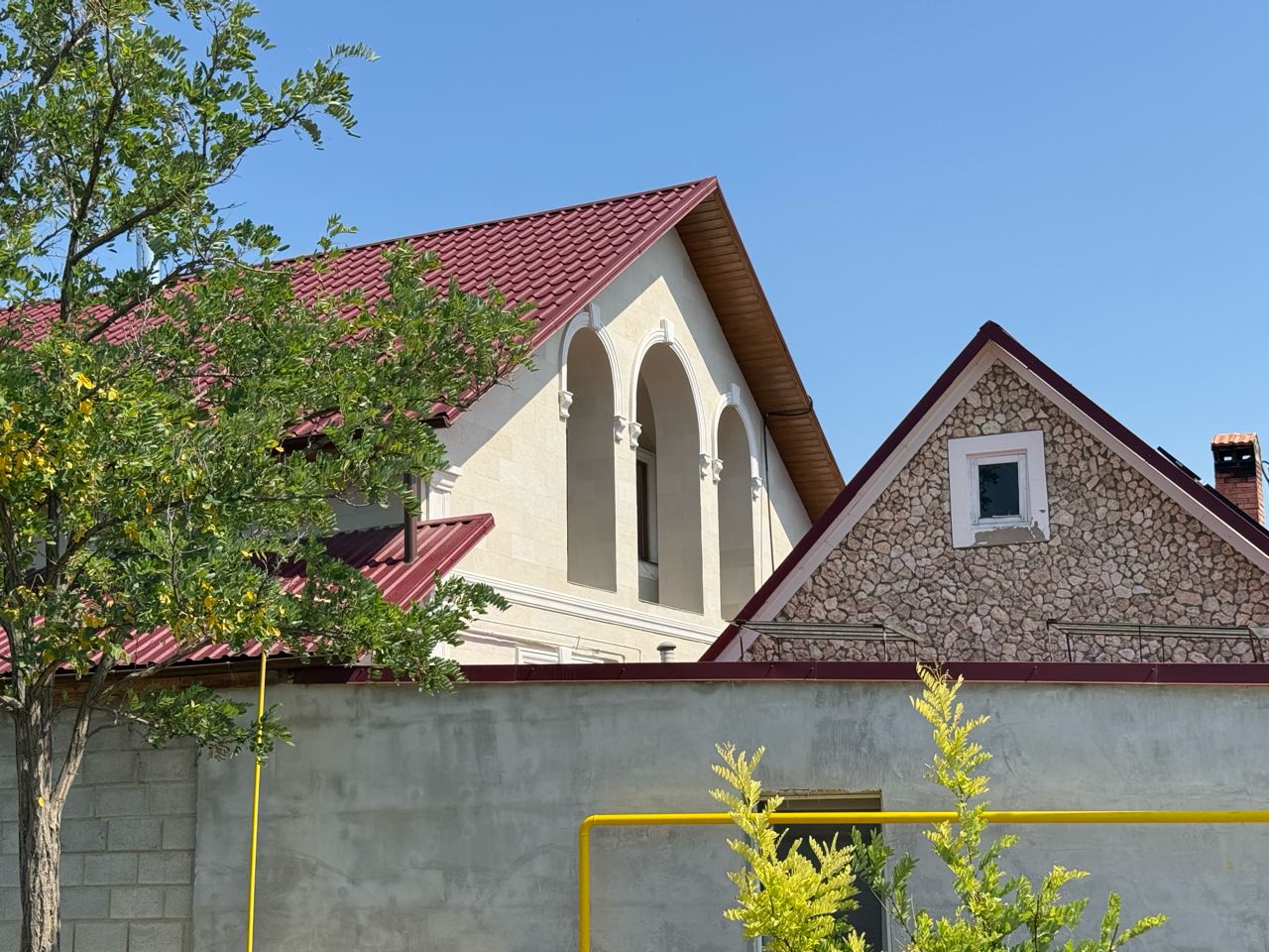 Cream house clad in light flexible stone, arches with white surrounds and a tiled roof