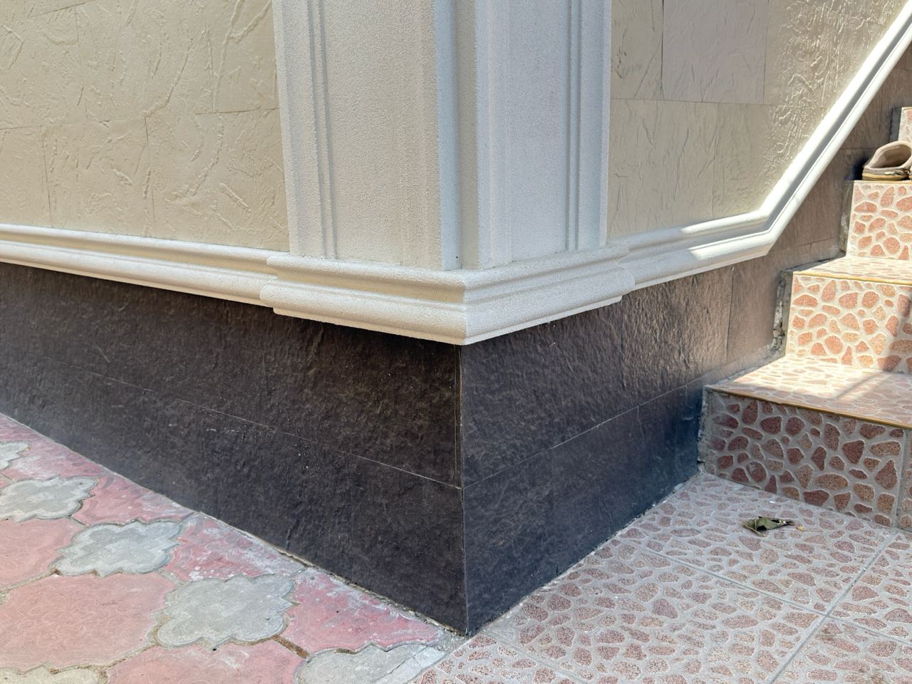 Plinth in dark-toned flexible stone contrasting with the light wall