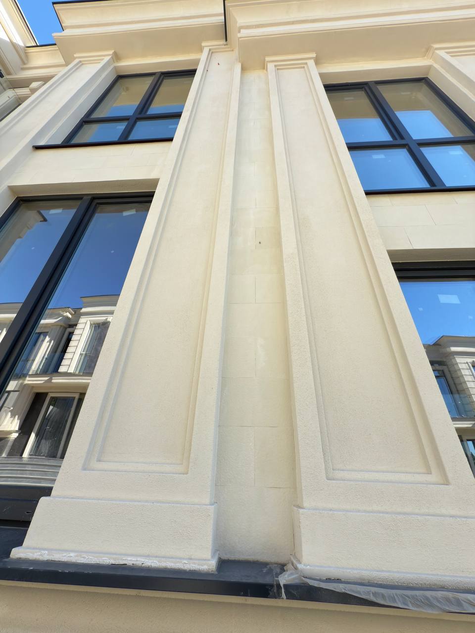 Fluted beige flexible stone pilaster between two tall black-framed windows