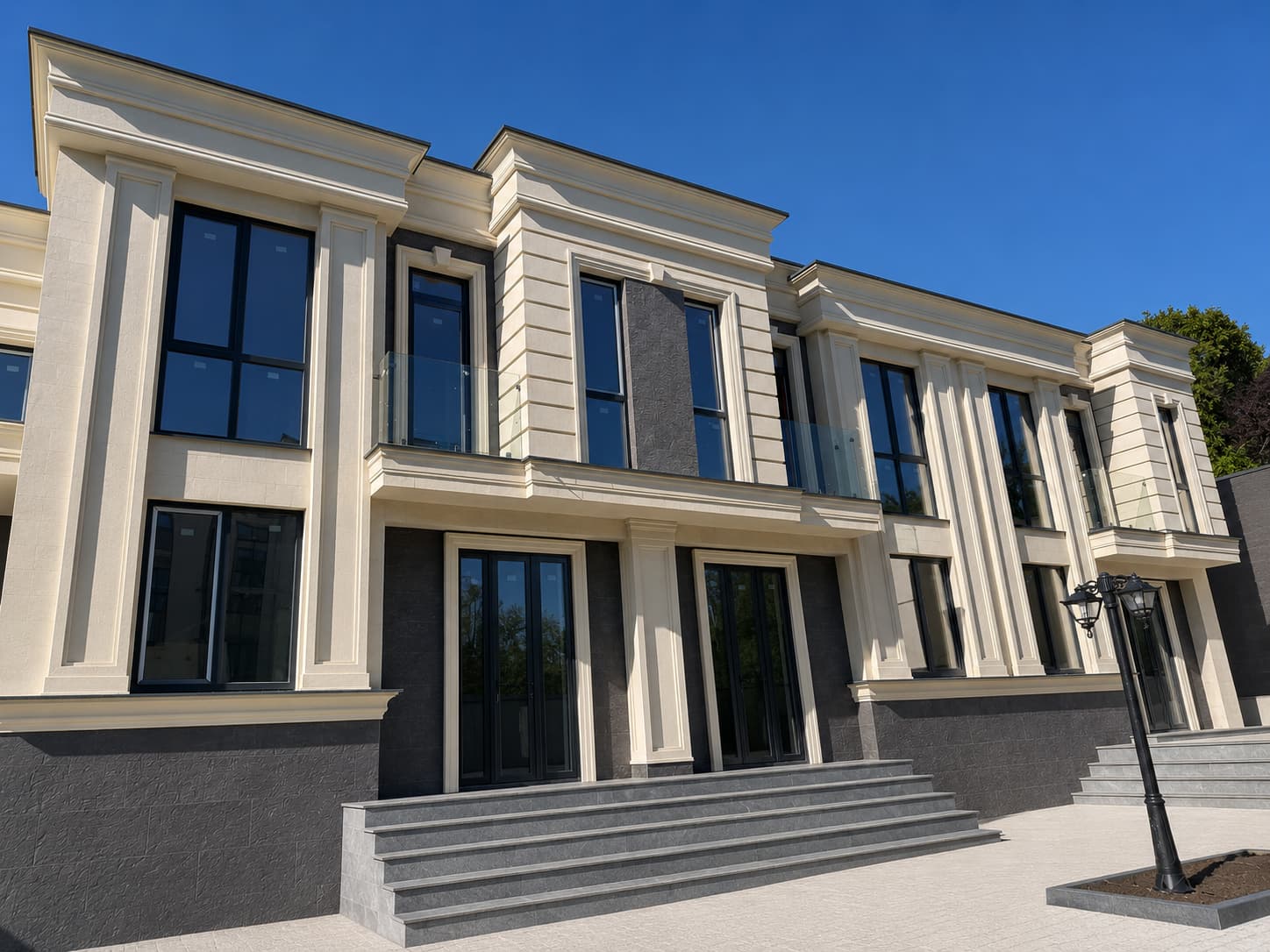 Row of houses with beige facades, anthracite vertical panels between the windows, plinth and steps