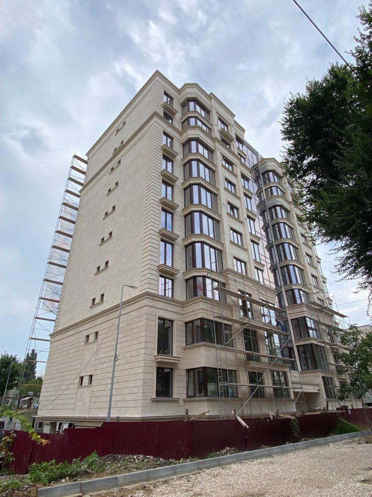 The block's tower with stacked bay windows and horizontal rustication in beige flexible tile, fence in front