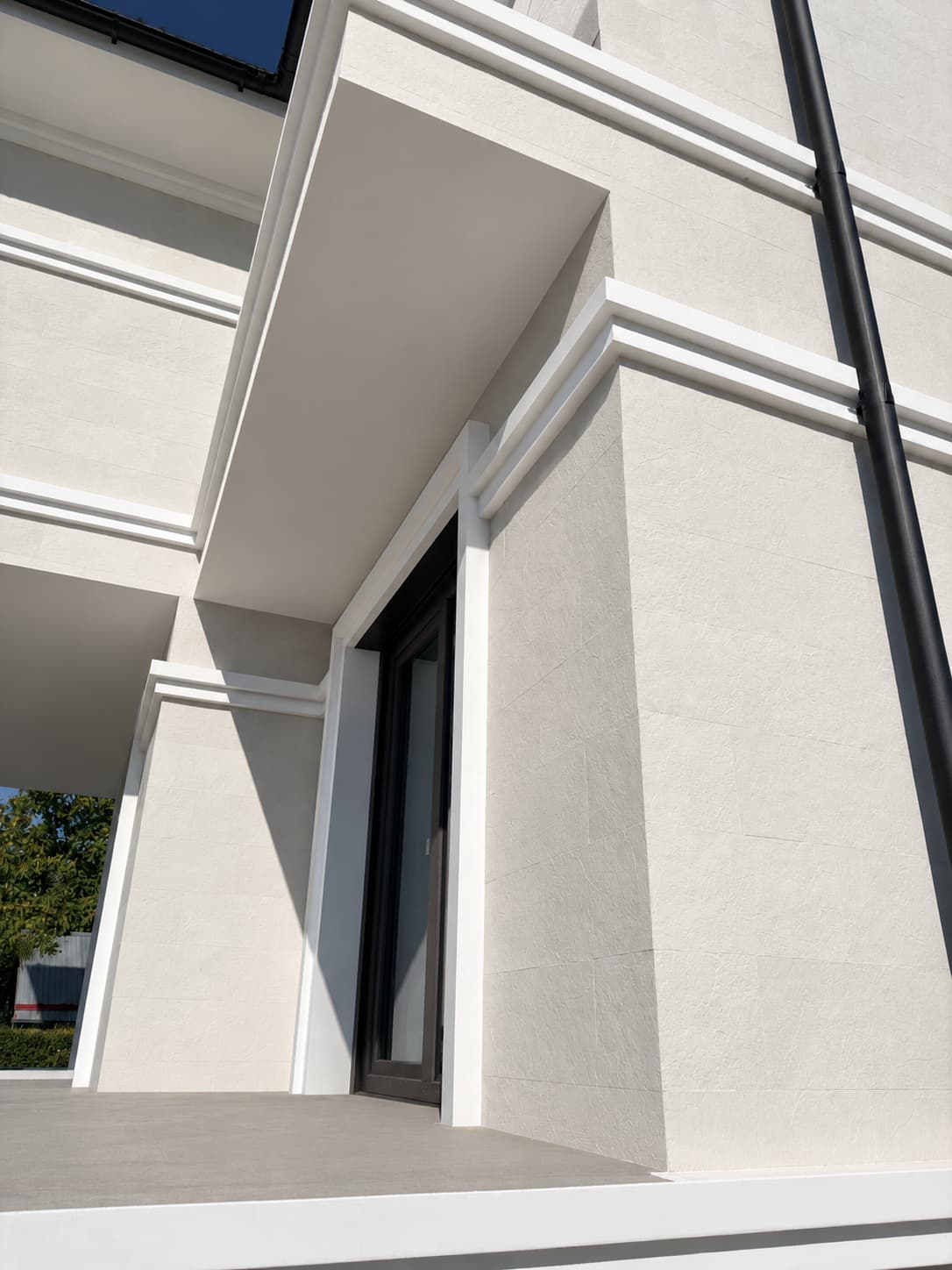 House corner clad in Mont Blanc flexible stone, white cornices and black window frames