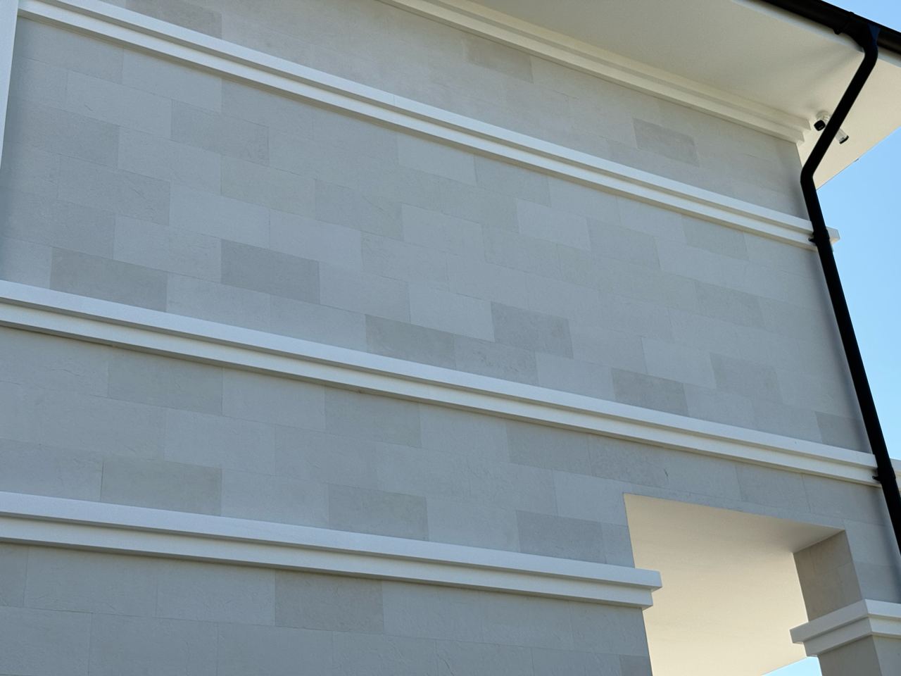 White belt and a field of flexible stone at the house corner against the sky
