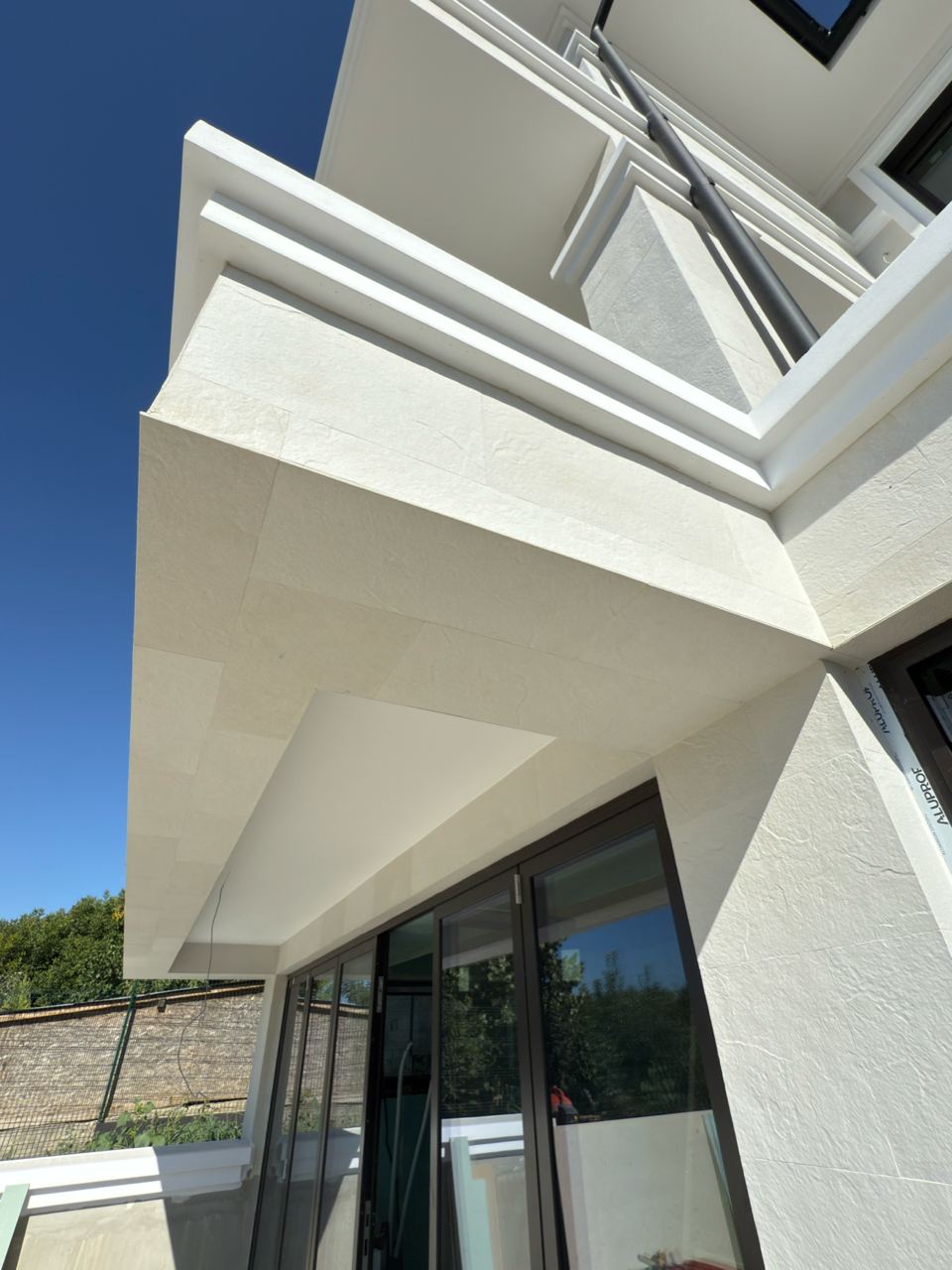 Corner of the entrance canopy from below, with glazing and white flexible stone