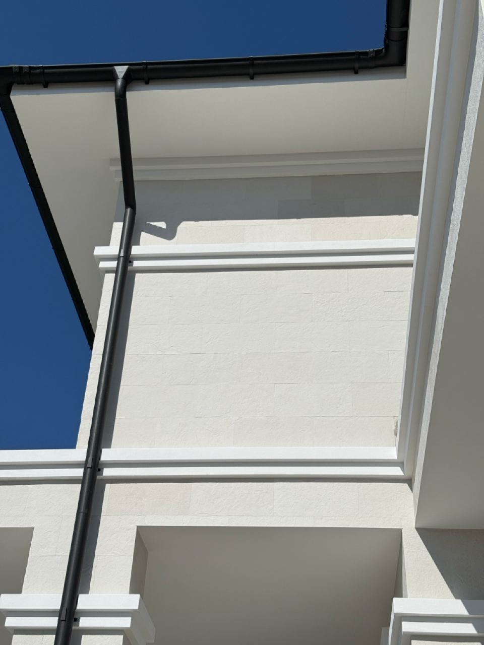 Upper corner with a white cornice and the underside of a balcony, light flexible stone