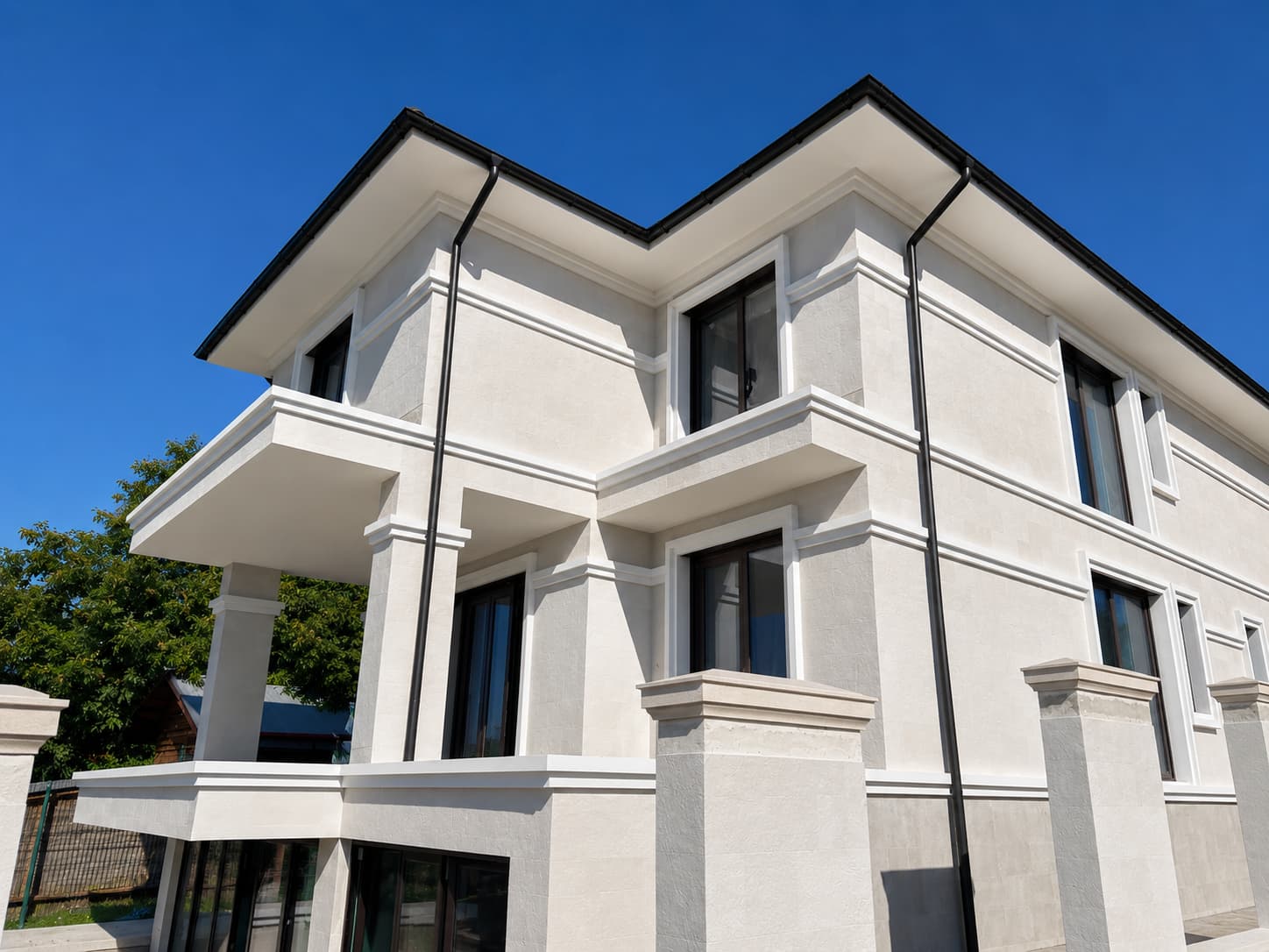 Three-storey house from below: Mont Blanc flexible stone between white cornices, a balcony and clear sky