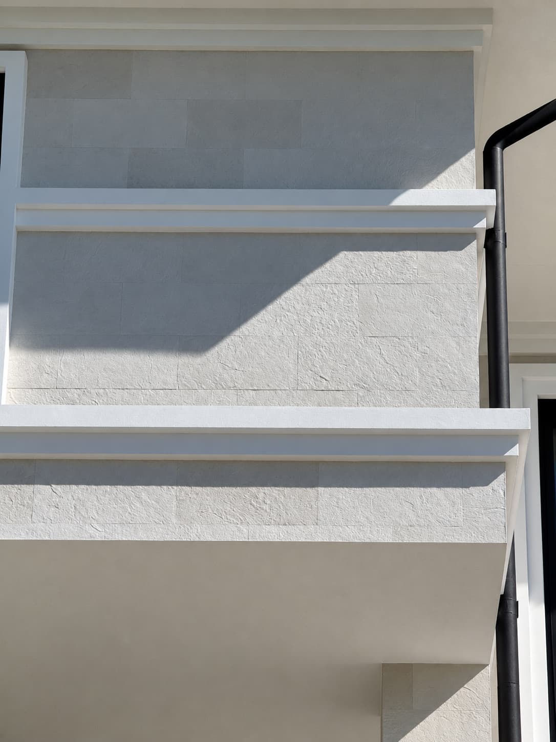Balcony parapet and upper corner in white flexible stone under a white band